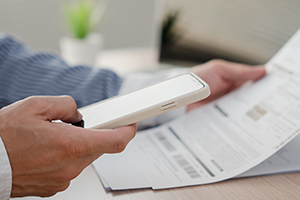 Man looking at bill, holding cell phone
