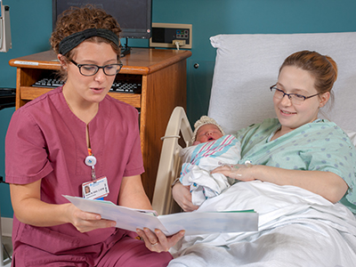 healthcare provider with patient and newborn in hospital room