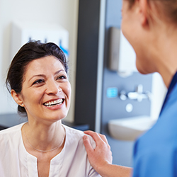 Female physician with hand on smiling female patient's shoulder