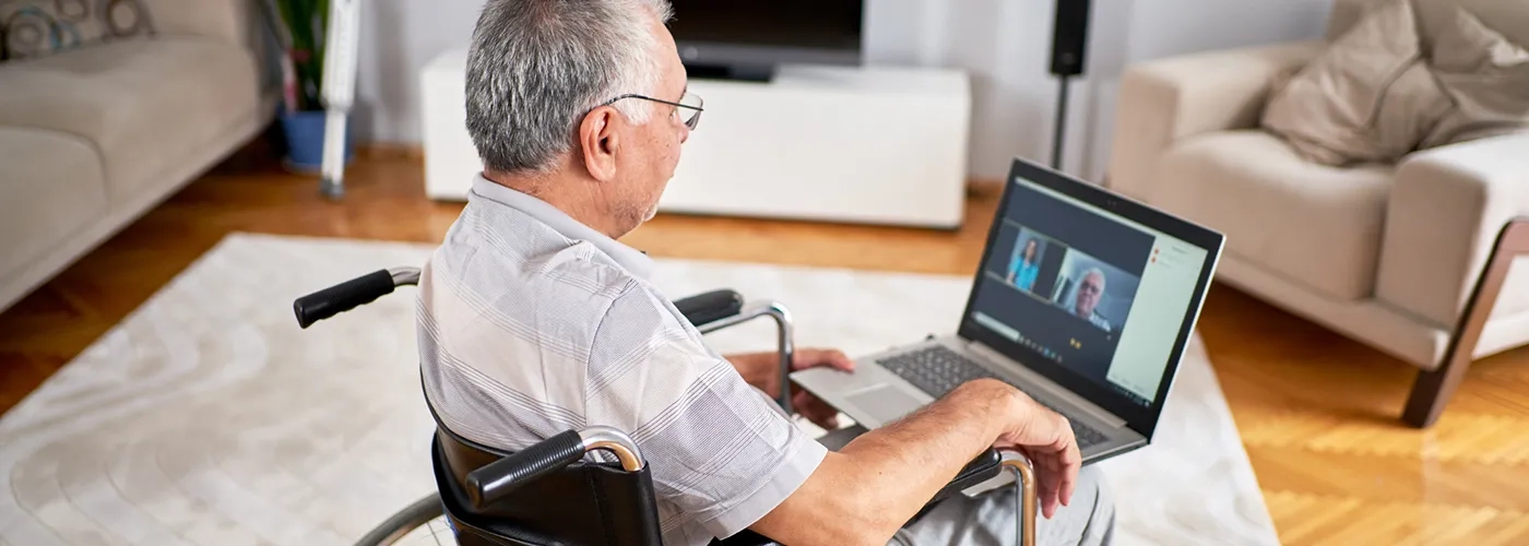 Older man in wheelchair on video call with healthcare provider