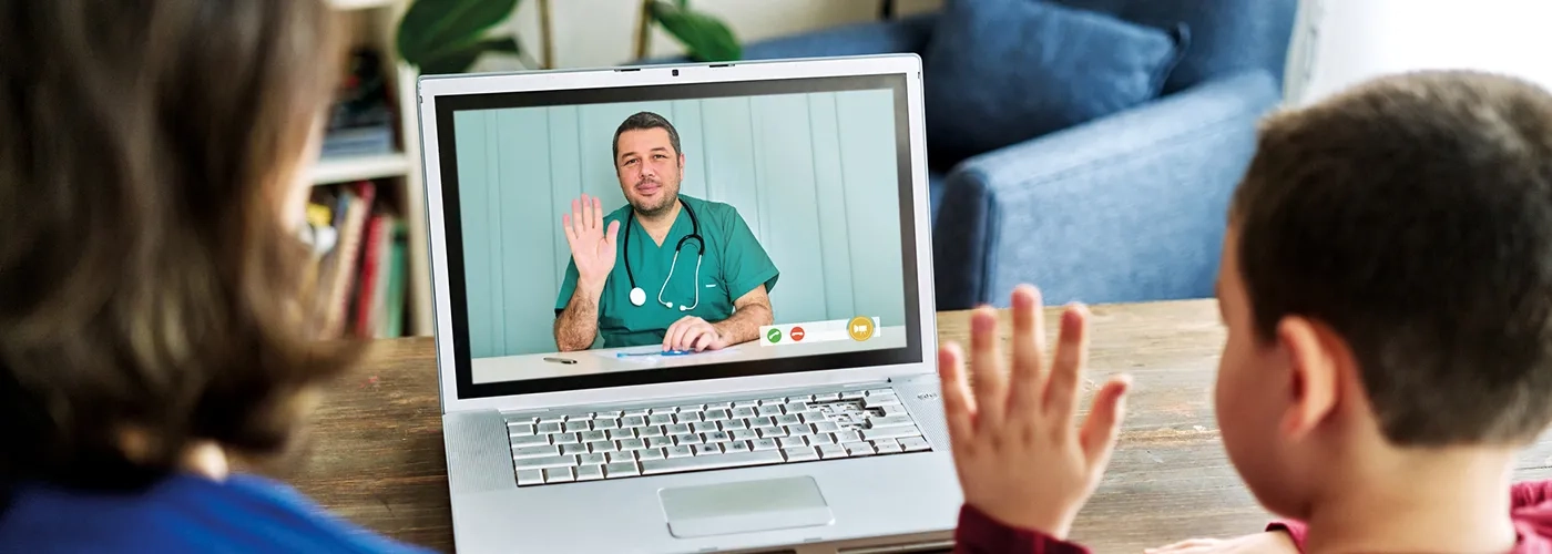 Woman and child on video call with healthcare provider; child and provider are waving at each other